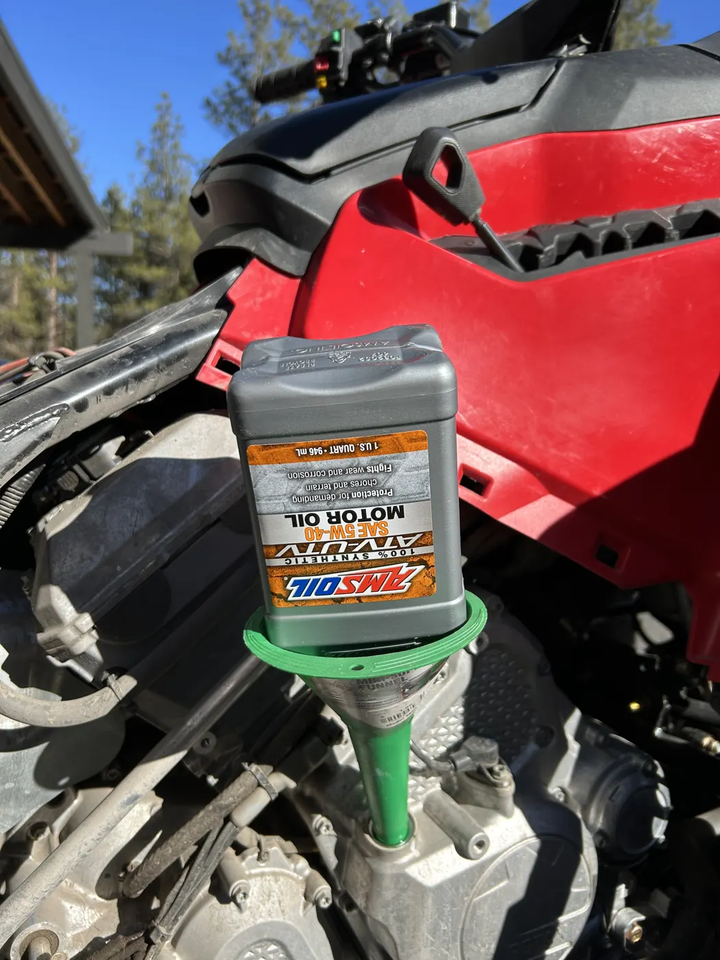 Pouring AMSOIL Synthetic ATV/UTV Motor Oil into an ATV through a funnel