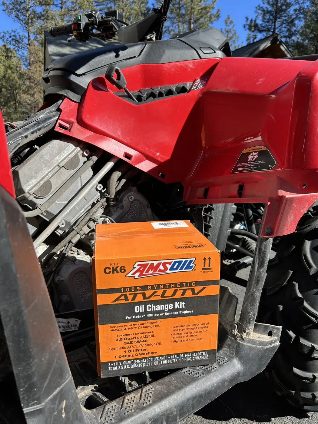 AMSOIL ATV/UTV Oil Change Kit box on the rack of a red ATV