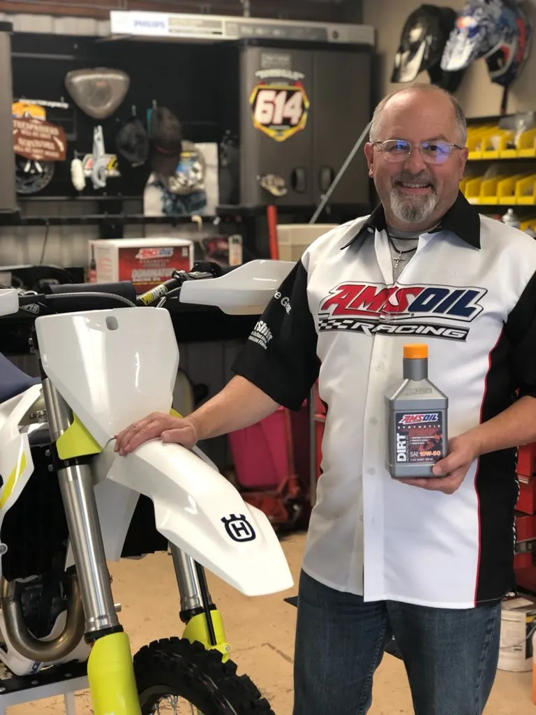 Mark Ossinger in an AMSOIL Racing shirt with a race bike